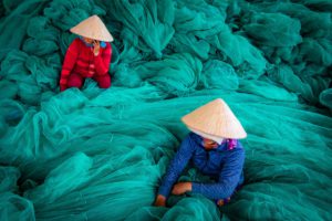 two women surrounded with green fish nets